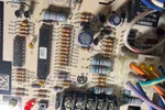 Heating Furnace Repair in Alpharetta 30009 by The Air Company of GA.  Close-up of a circuit board with resistors, capacitors, chips, and colorful wires connected to terminals.