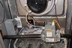 Residential AC Maintenance in Norcross by The Air Company of GA. Open furnace showing gas valve, burner assembly, and wiring inside metal housing for heating system.