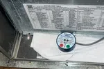 Furnace Heating Repair in Atlanta Decatur 30030 by The Air Company of GA.  White Honeywell safety sensor attached inside metal HVAC unit with wiring and cloth nearby on wooden floor.
