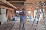 Man posing inside an unfinished wooden interior construction site with tools and ladder.  HVAC Repair in Atlanta 30341 by The Air Company of GA.