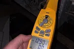 Commercial HVAC Repair in Atlanta 30324 by The Air Company of GA.  Yellow digital clamp meter measuring 12.90 amps on electrical wiring in a dark enclosure.
