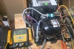Commercial HVAC Repair in Smyrna 30080 by The Air Company of GA.  HVAC compressor unit on wooden board connected to Fieldpiece gauge manifold with yellow hoses and copper pipes.
