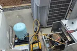 Wine Cellar Repair in Marietta 30064 by The Air Company of GA.  HVAC unit with refrigerant gauges, a blue refrigerant canister, and diagnostic tools on concrete next to outdoor condenser.