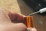 Furnace Heating Repair in Atlanta Decatur 30030 by The Air Company of GA.  Hand holding small copper cylinder keychain with keys and a black bag in soft background on wooden surface.