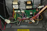 Heating Control Board Repair Atlanta 30324 by The Air Company of GA.  Close-up of electrical control board with colorful wires inside an appliance metal housing with warning labels.