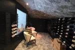 Wine Cellar Installation in Atlanta by The Air Company of GA.  Cozy wine cellar with stone floor, sloped stone ceiling, wine racks, two chairs, and wooden barrel table.