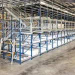 Spacious warehouse interior with metal shelving, stacked materials, and a forklift on concrete floor.