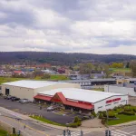 Aerial view of a Lowe's home improvement store with parking lot and surrounding roads under a cloudy sky.