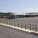 Large industrial yard with metal storage racks and warehouse buildings under a clear sky