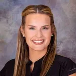 Smiling dental professional in Rivertown Dental Care uniform against a blurred gray background