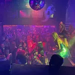 Crowded nightclub with people dancing and colorful lights under a large disco ball during a party
