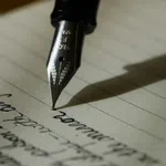 Close-up of a fountain pen writing cursive text on lined paper with shadow cast to the side