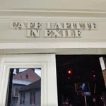Entrance of Cafe Lafitte in Exile with white wooden doors and reflective glass showing buildings outside.