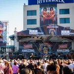Outdoor music festival on Mike's Amazing stage at Riverwalk with large crowd enjoying live band performance.