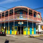 Colorful two-story building with yellow and blue walls and pink balcony railing at street corner in sunny weather
