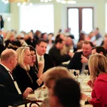 People enjoying a social gathering at a restaurant with conversations and dining in a warm, well-lit atmosphere.