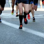 Close-up of runners' legs and feet in athletic shoes on a city road during a race event