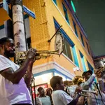 Street musicians playing trumpets and trombones during a lively outdoor jazz performance at night.