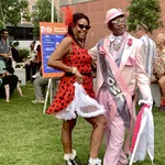 Couple dressed in vibrant retro outfits enjoying an outdoor festival on a sunny day with people relaxing nearby