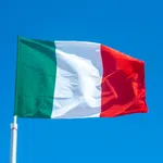 Italy national flag waving against a clear blue sky background outdoors.