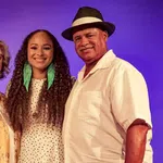Smiling three generations family portrait with purple background and casual summer clothing