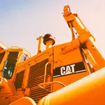 Close-up of a yellow Caterpillar bulldozer with visible CAT logo under bright sunlight.