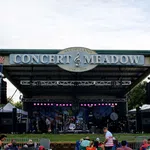 Outdoor stage setup at Al Copeland Concert & Meadow with banners for Uncle Sam Jam event and audience seating.