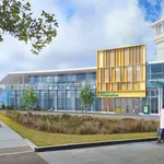 Modern imaging center with glass facade, yellow accent panels, landscaped front, and people walking outside.