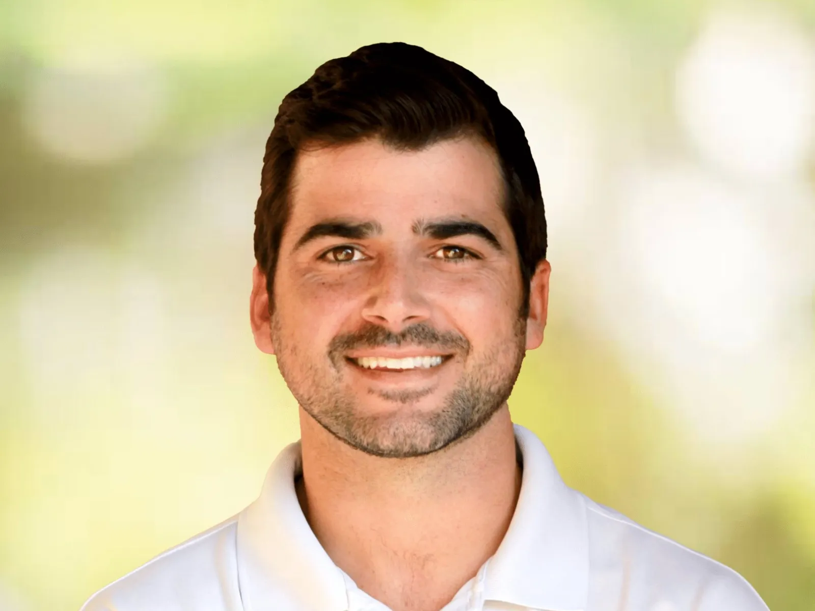 Smiling man in white polo with Dr William Beis and 100% chiropractic logo on shirt against blurred background