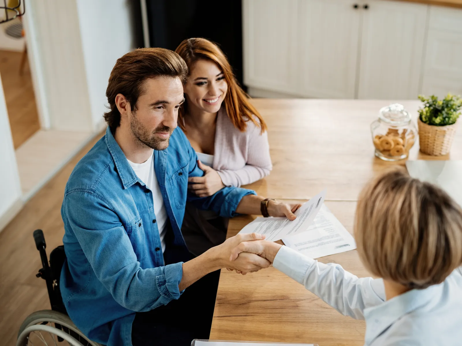 a man and a woman sitting at a table with a child and a man looking at a paper