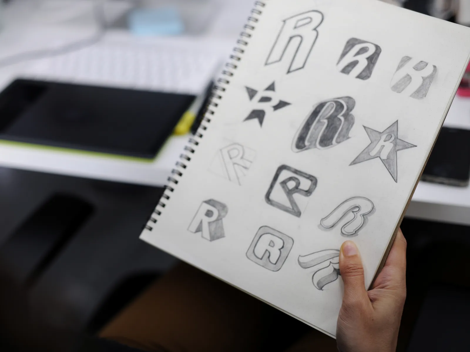 a hand holding a piece of paper with drawings on it