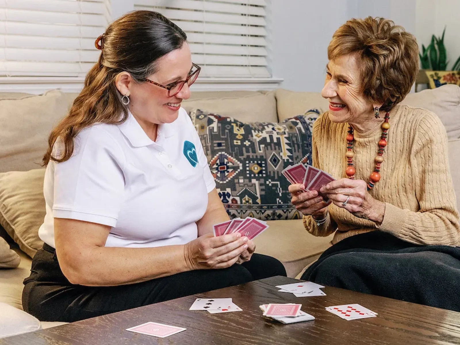a couple of women playing cards on a couch