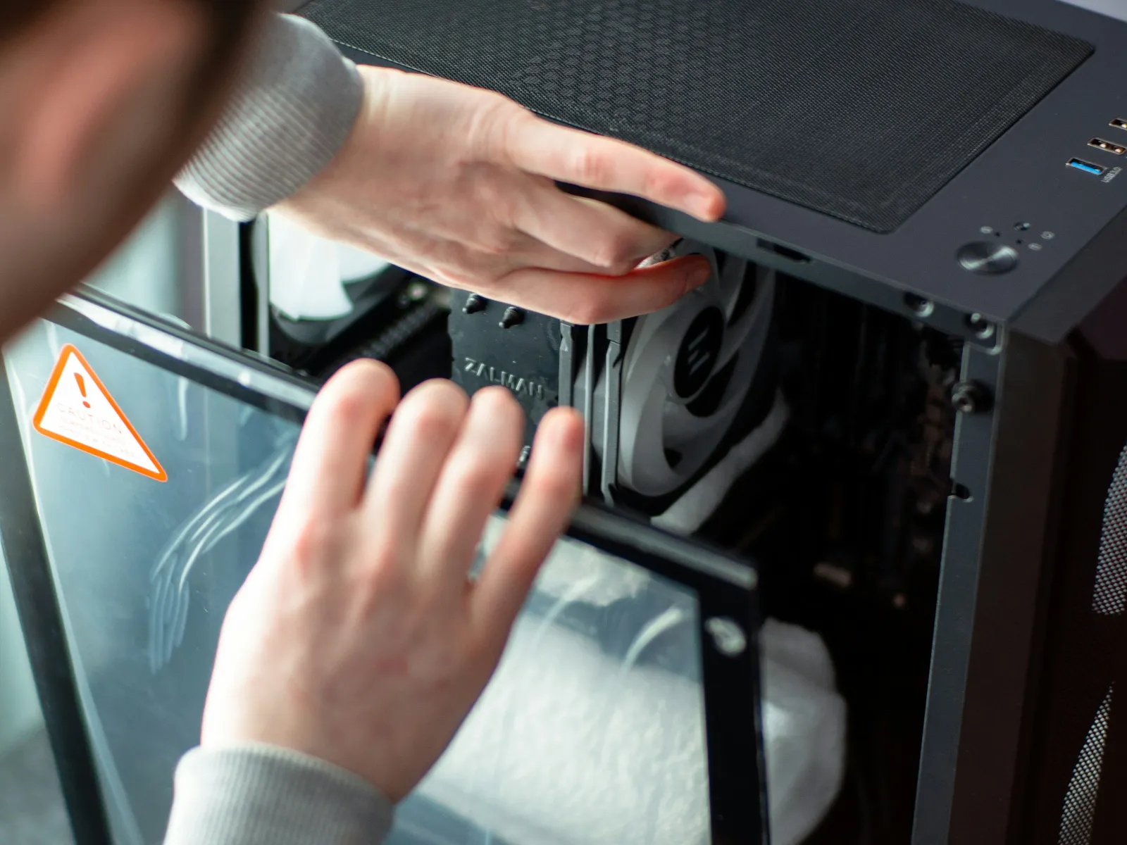 Person installing a cooling fan inside a desktop computer tower with an open side panel.