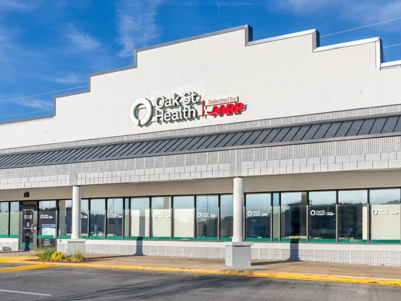 Oak St. Health medical clinic exterior with clear blue sky and storefront windows in a commercial plaza