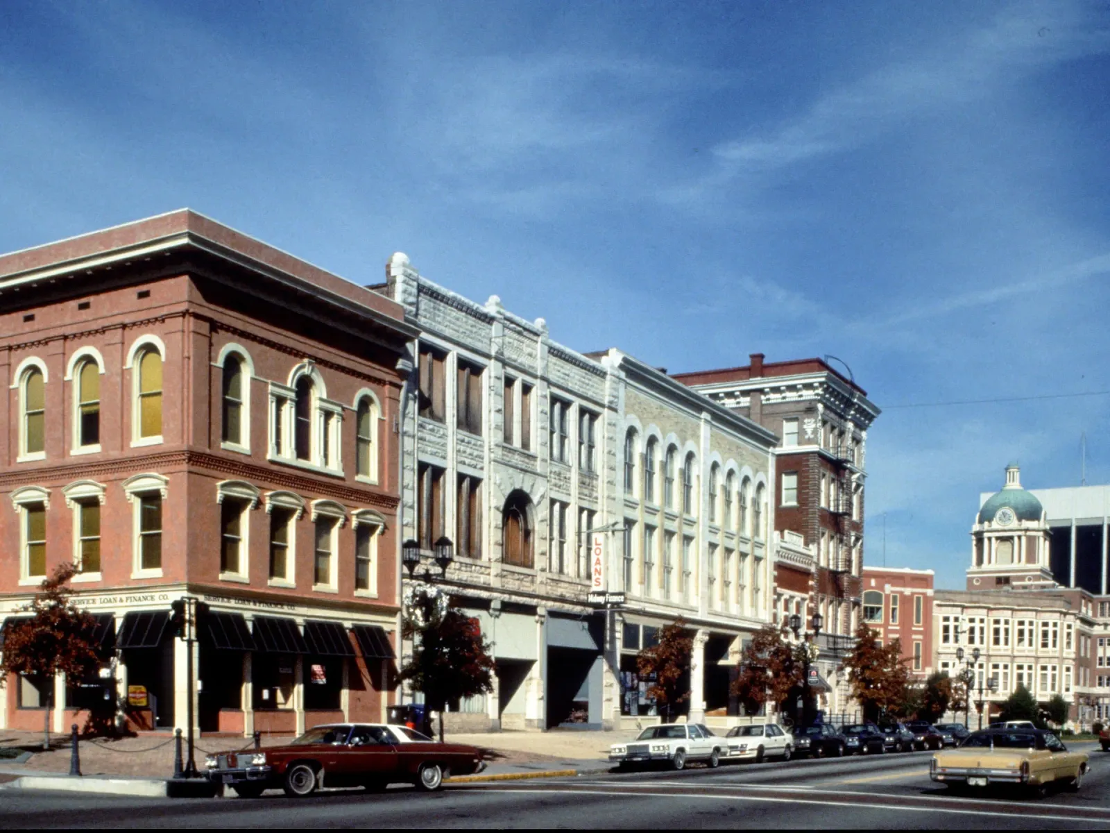 Historic downtown street with late 19th-century brick and stone buildings under a clear blue sky