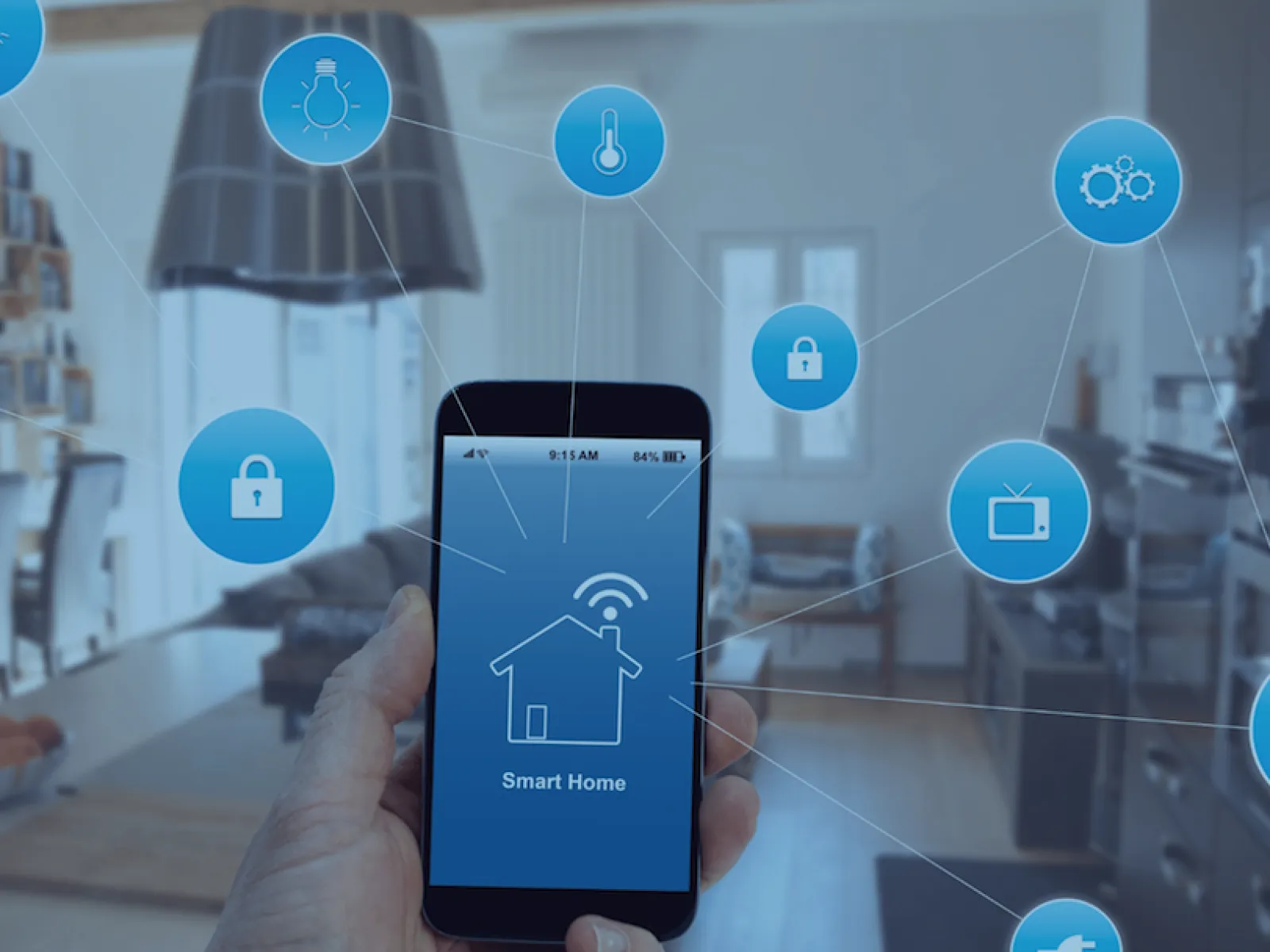 Hand holding smartphone displaying smart home app with icons for security, lighting, temperature, and appliances in a modern interior.