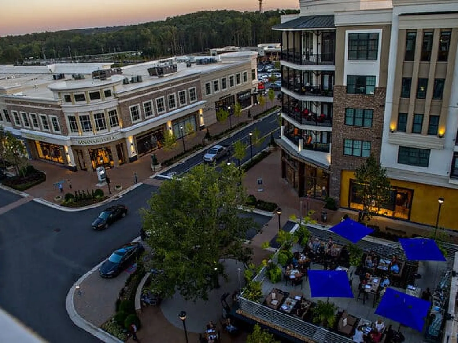 Urban street scene with modern buildings, cars, and outdoor dining area in the Avalon District