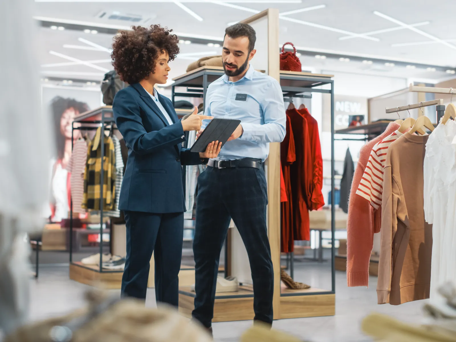 a man and a woman looking at a book in a clothing store