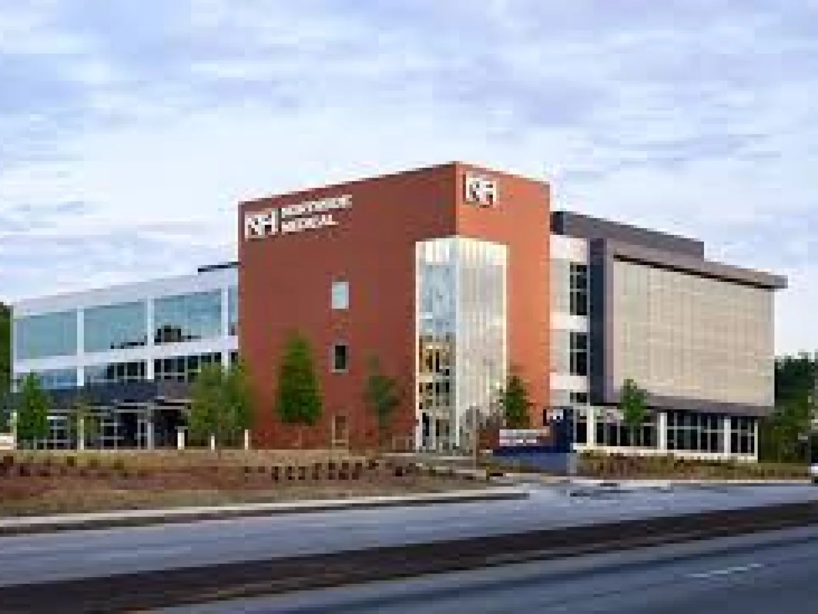 Modern brick and glass building of Northside Medical on a clear day with surrounding greenery and road in front.