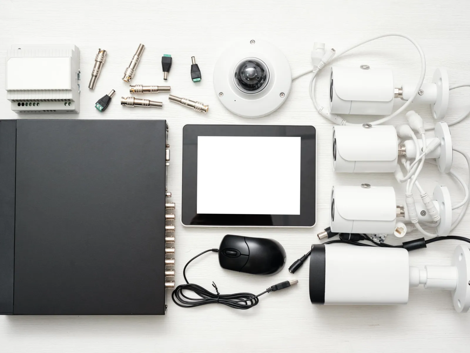 Home security system components including cameras, control panel, cables, connectors, and a tablet with mouse on white background