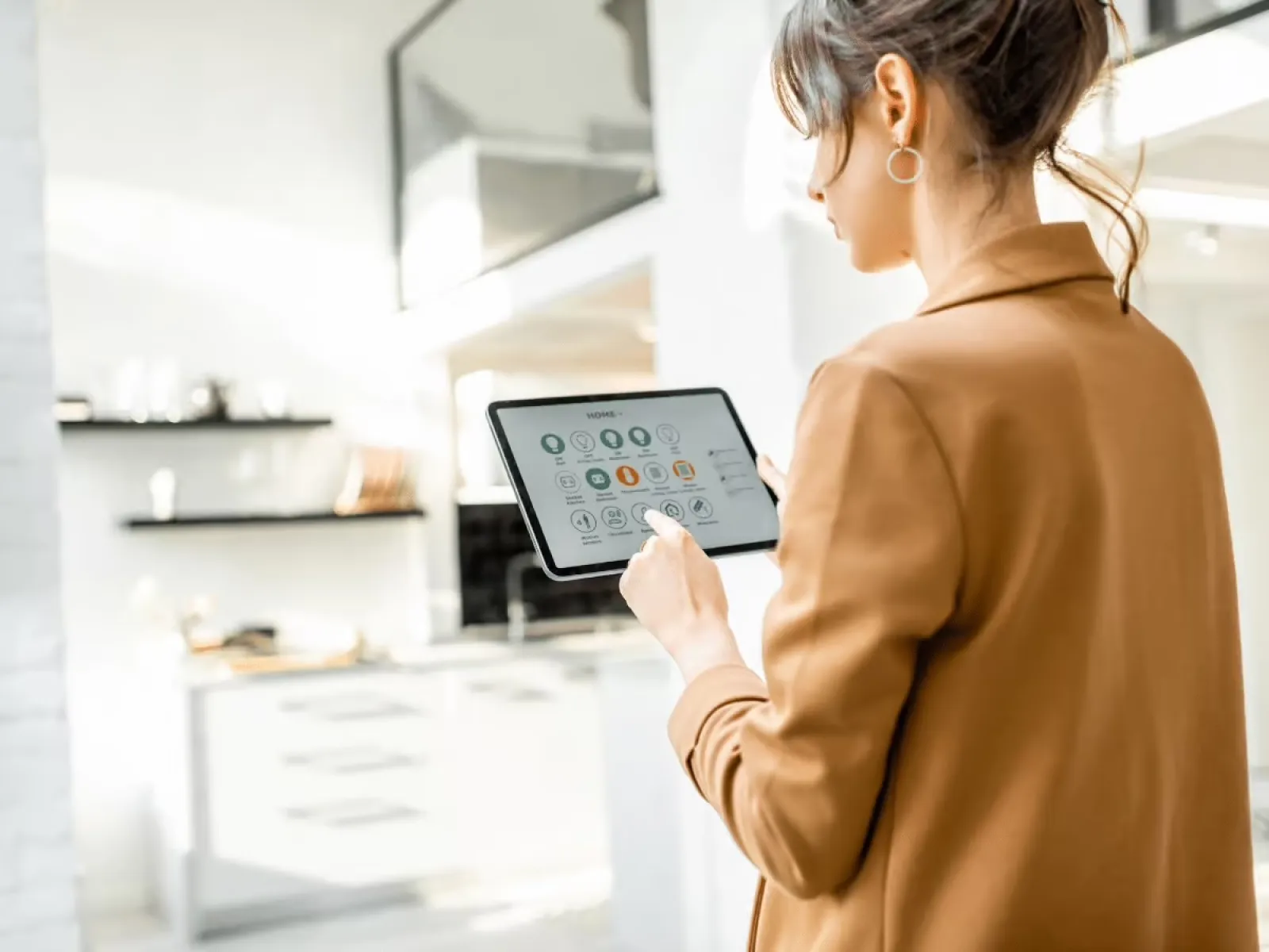 Woman using a tablet to control smart home devices in a modern kitchen setting