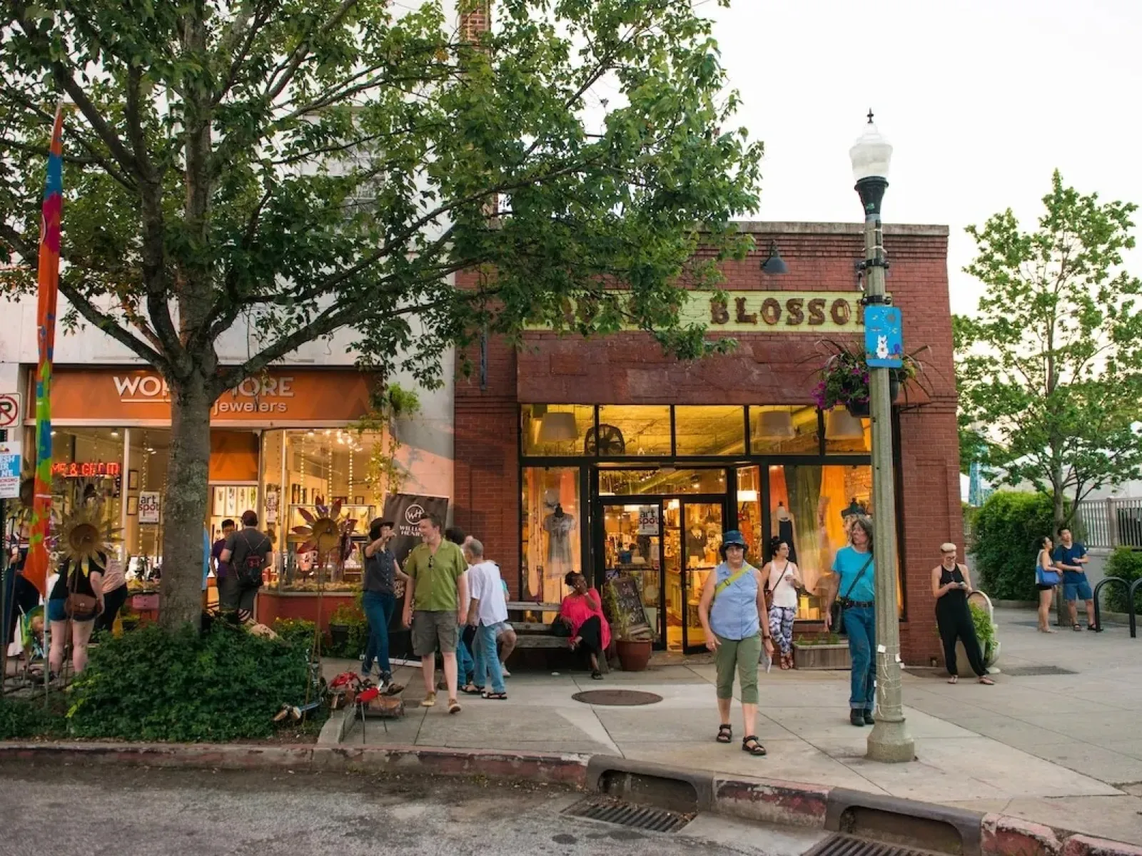 People walking and shopping outside local stores on a lively downtown street during daytime.