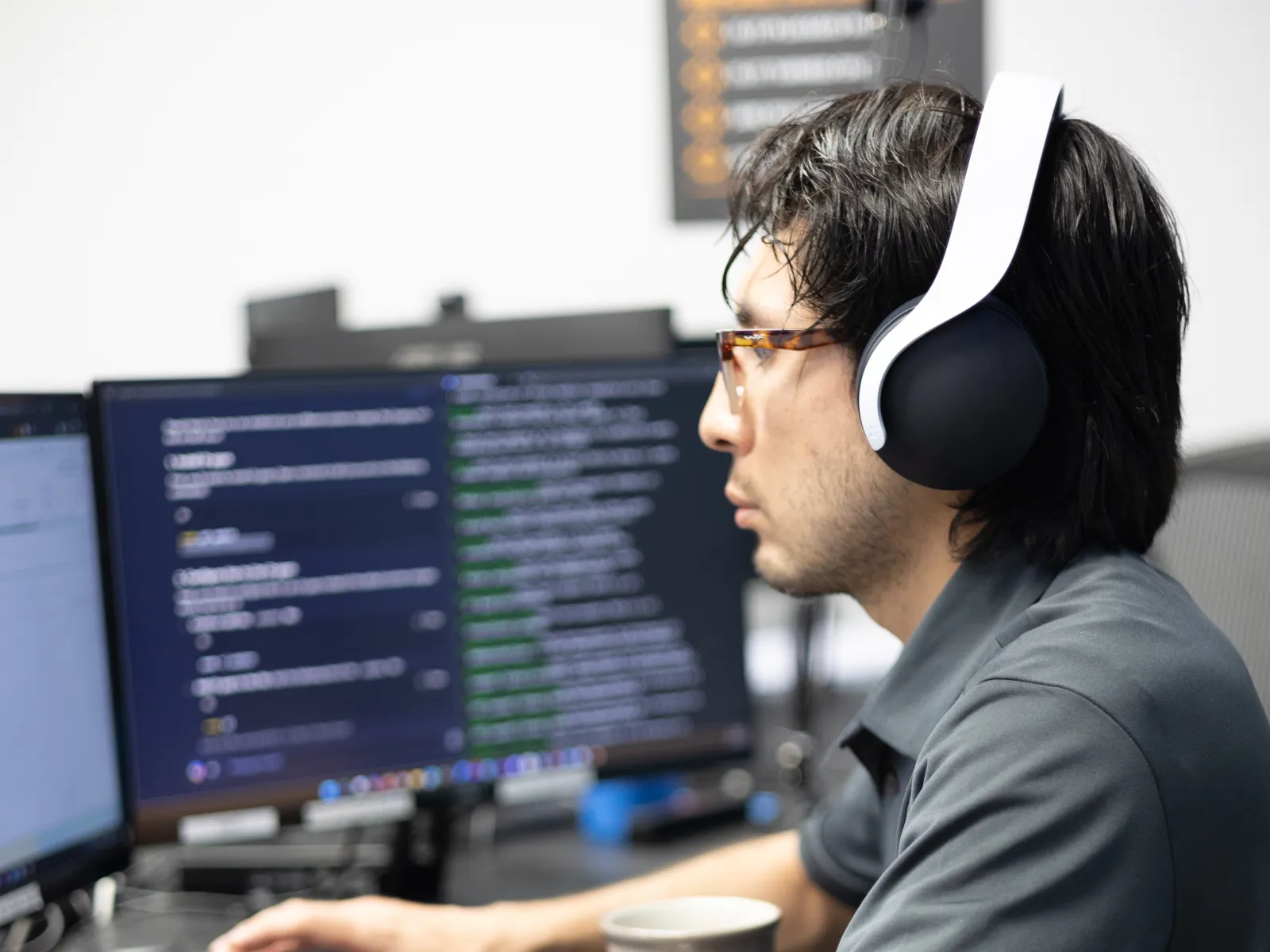 a person wearing headphones and sitting at a desk with a cup of coffee