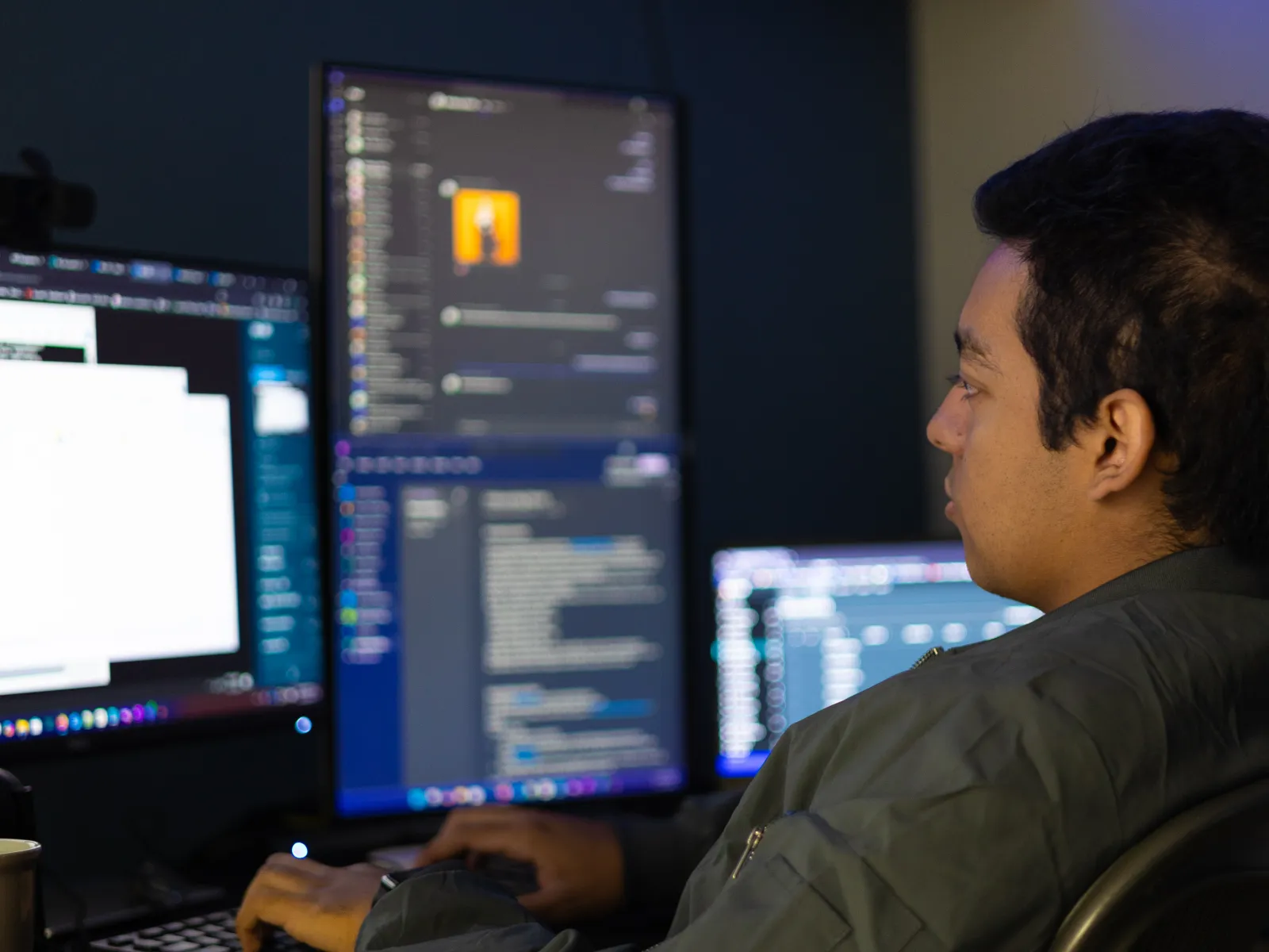 a man sitting at a desk with several monitors