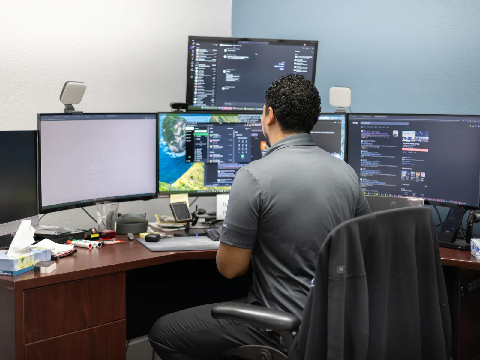 a man sitting at a desk with several monitors