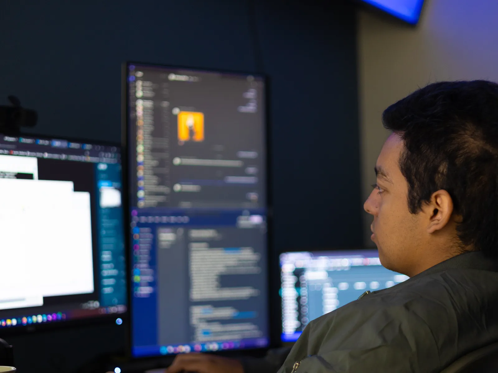 a man sitting at a desk with several monitors