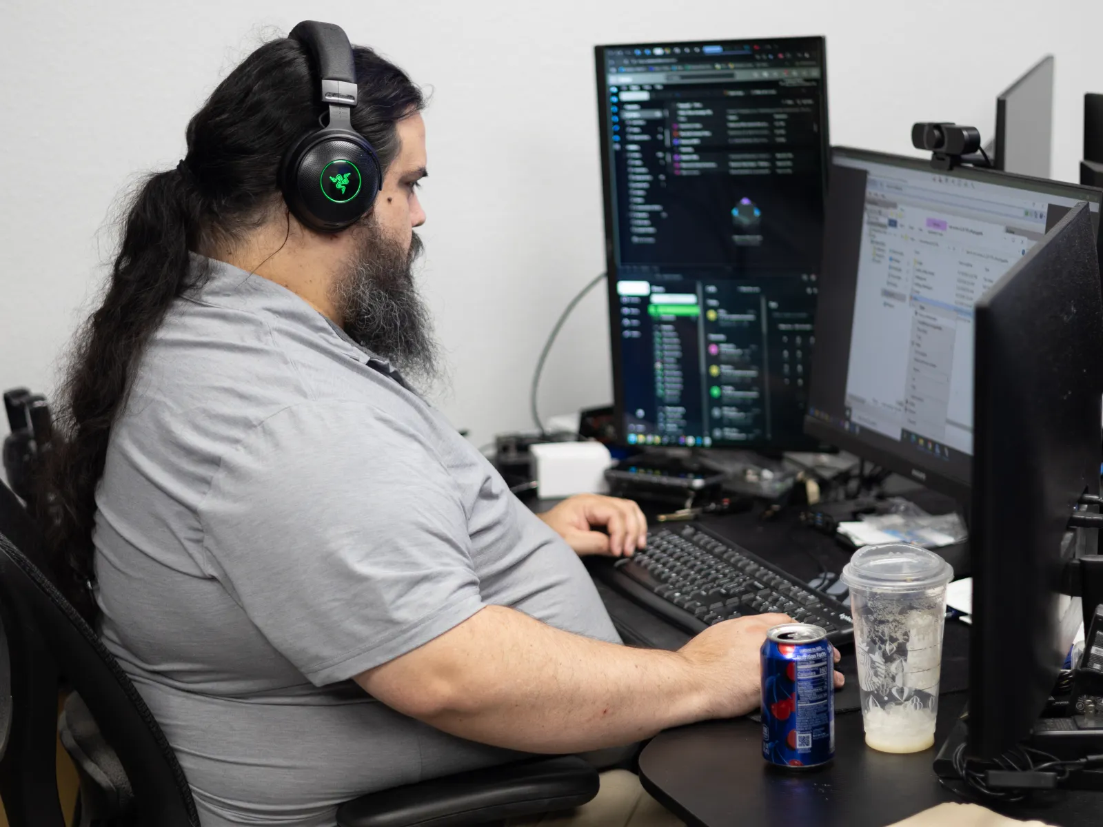 a person sitting at a desk with a computer and headphones on