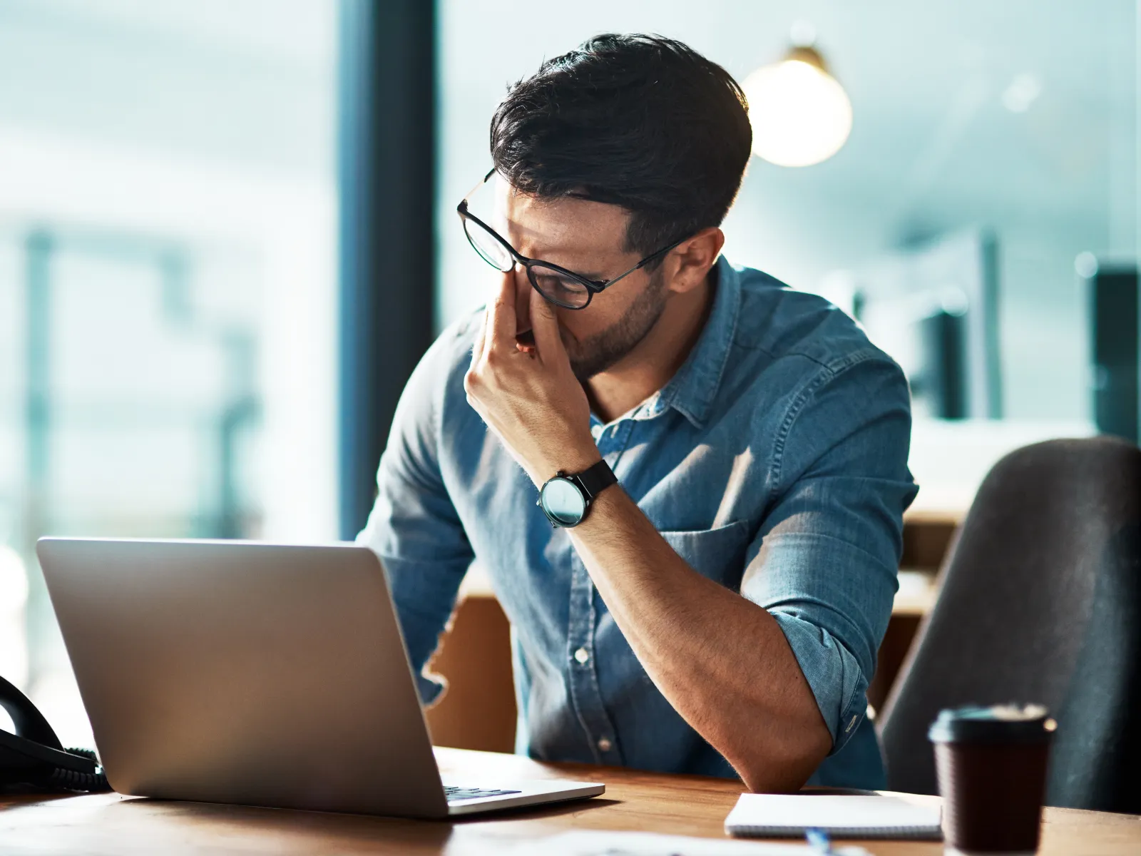 a man sitting at a desk with his hand on his face