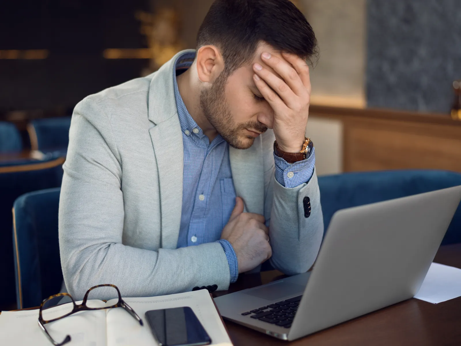 a person with the hand on the face looking at a laptop