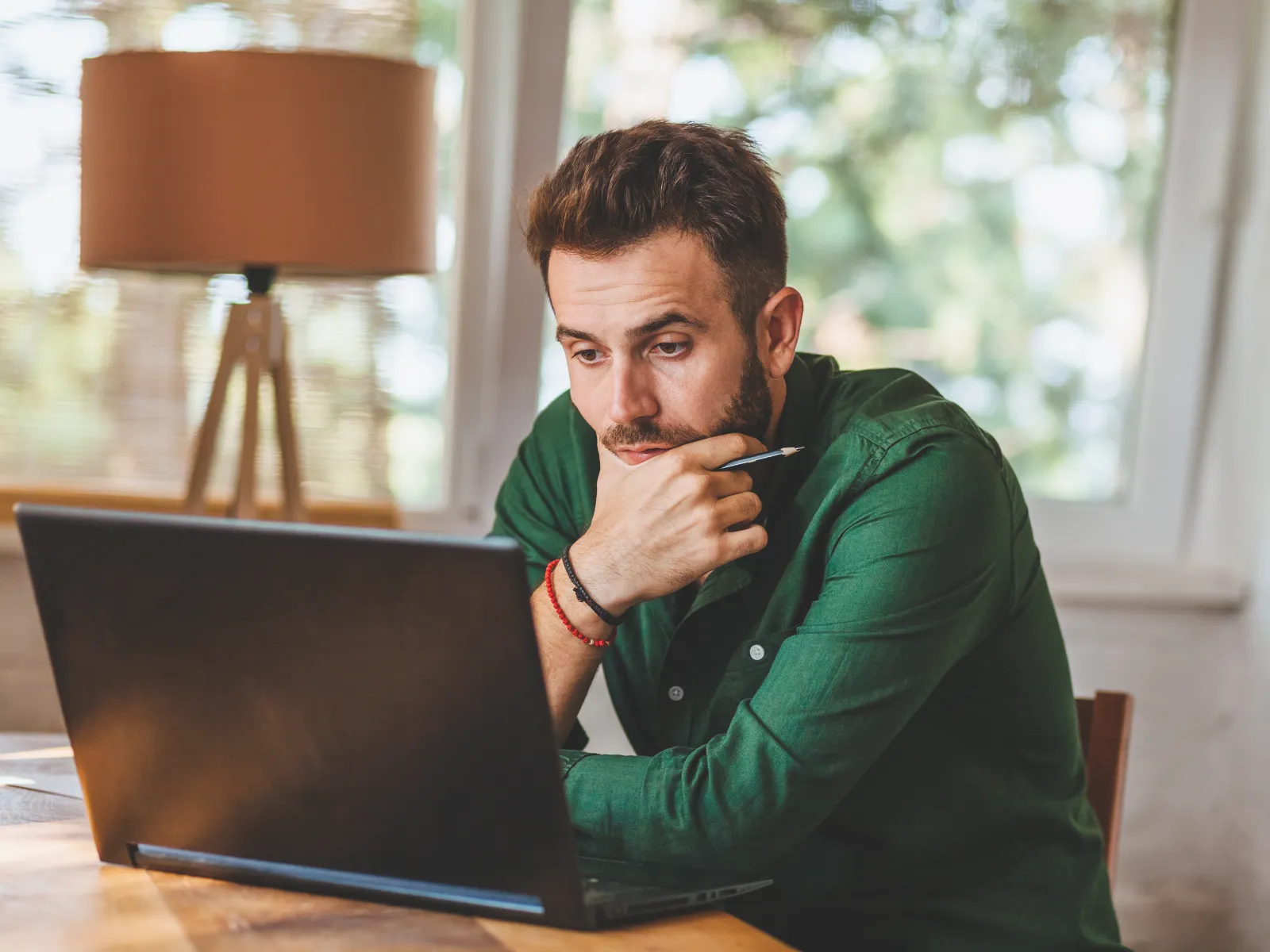 a person sitting at a table with a laptop and smoking a cigarette